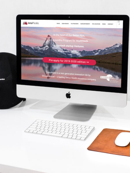 iMac posé sur un bureau allumé avec la page internet du site Innopeaks